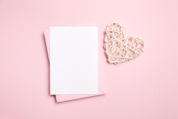 Card mockup, empty Valentines Day love letter with white heart on light pink background, top view, flat lay. Blank wedding invitation, white holiday greeting card