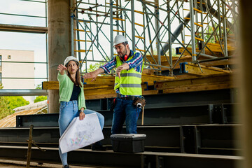 Woman architect explaining blueprint to supervisor at construction site. Engineer talking to contractor.