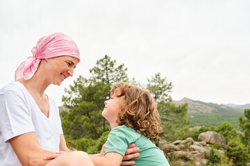 Mother with cancer and son looking at each other relaxed on the mountain.