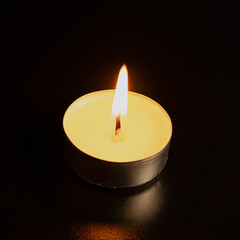 Candles in the dark. Round floating candle. candles in an aluminum case. burning aluminum tea candle isolated on black background. romantic atmosphere