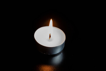 Candles in the dark. Round floating candle. candles in an aluminum case. burning aluminum tea candle isolated on black background. romantic atmosphere