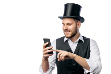 Man in cylinder hat, black waist and white shirt scrolling smartphone isolated on white background