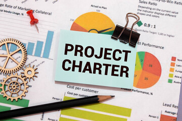 PROJECT CHARTER text on paper with calculator, notepad, coffee ,pen with graph.