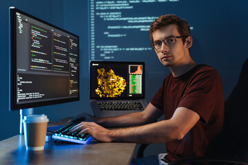 Portrait of Intelligent male programmer working on pc writing brand new code at his home office,...