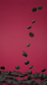 Granos de caf&eacute; cayendo en c&aacute;mara lenta en un fondo  rojo