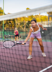 Sporty teenage girl tennis player playing tennis at court outdoor. View through tennis net
