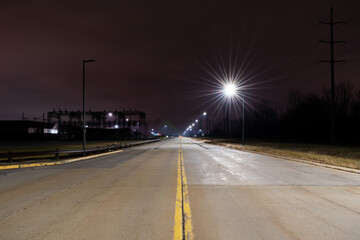 Long road at night lit by streetlights.