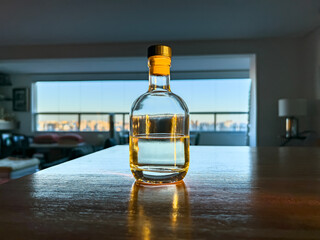 Transparent bottle container without labeling. In the background, window and blurred city.