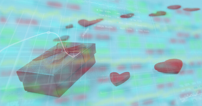 Image of gift box and heart shapes over moving graphs and trading board