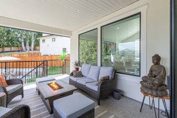 A luxurious spacious deck with stylish patio furniture and a table fire-pit heater