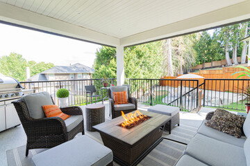 A luxurious spacious deck with stylish patio furniture with a fire pit table heater.
