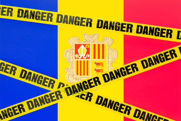 Tape with inscription danger against flag of Andorra. Concept of dangerous entering of Andorra country for some reason