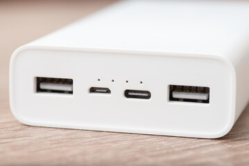 Close up shot of white modern powerbank on the table. External battery with four usb ports - type...