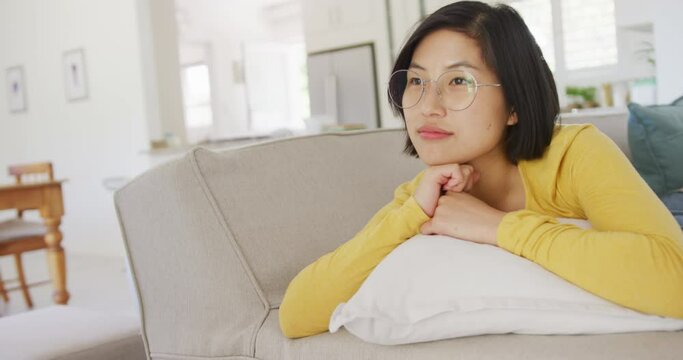 Happy asian woman lying on couch in living room