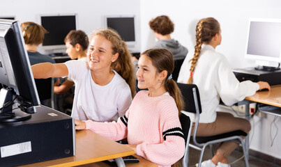 Obraz premium Portrait of two schoolgirls engaged in the classroom at a informatics lesson at the computer