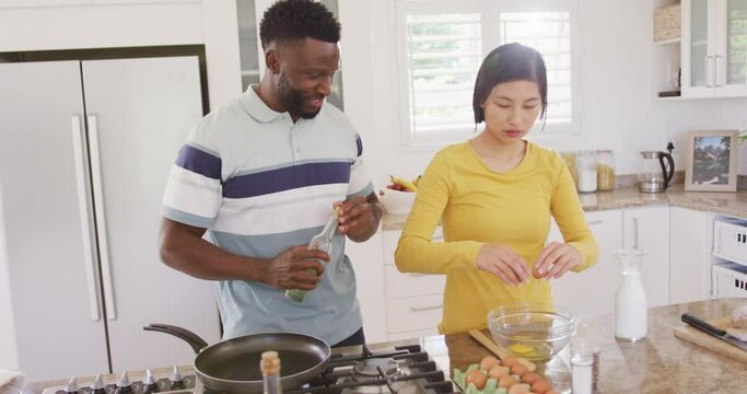 Happy diverse couple cooking and preparing breakfast in kitchen