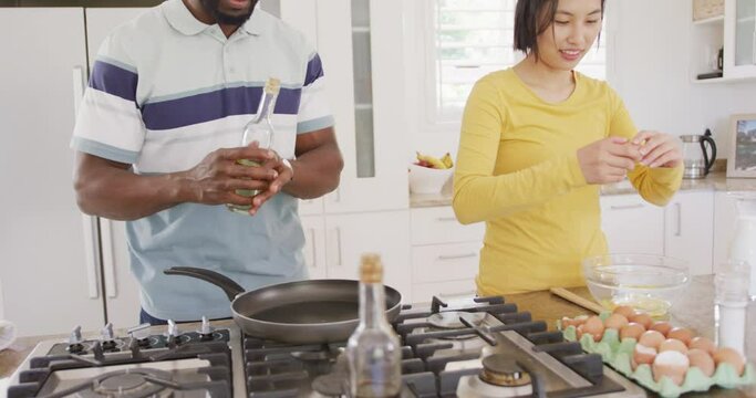 Happy diverse couple cooking and preparing breakfast in kitchen