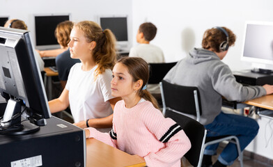 Fototapeta premium Portrait of two schoolgirls engaged in the classroom at a informatics lesson at the computer