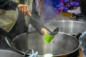 Woman pouring hot mulled wine on Christmas market.