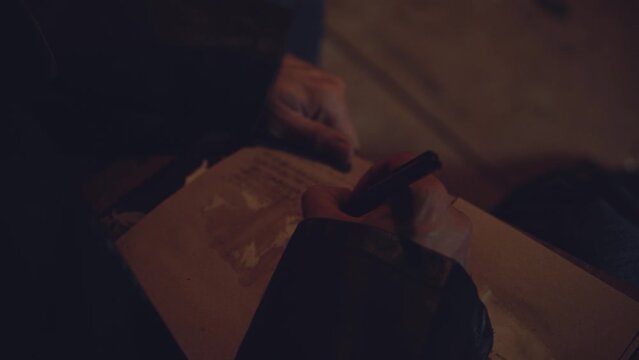 Adult seriously man with beard write old diary wear a vintage leather jacket in retro small fishing house of wood at deep night. Vintage a kerosene lamp fire