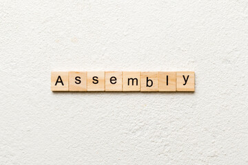 ASSEMBLY word written on wood block. ASSEMBLY text on cement table for your desing, concept