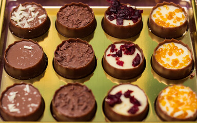 Golden box with delicious chocolate candies on purple table