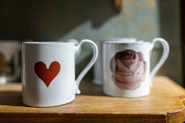 White porcelain mugs and saucers with a red heart print. Liberty shop.