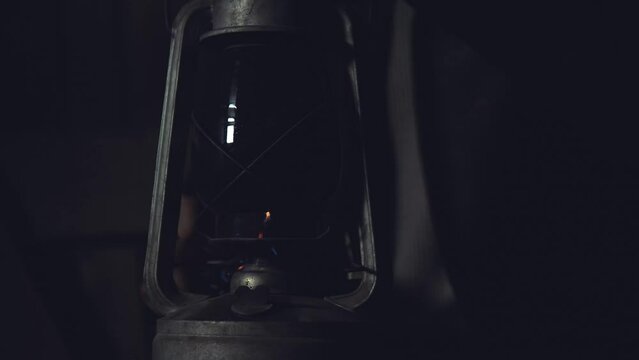 Adult seriously man with beard fire kerosene lamp wear a vintage leather jacket in retro small fishing house of wood.