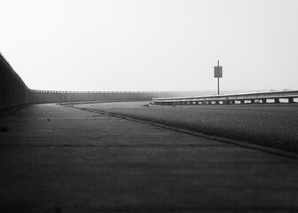 Black and white photo of a roadway disappearing into fog