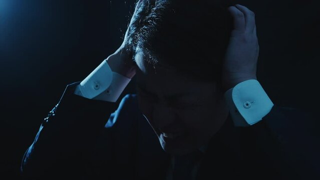 頭を抱えて苦しんでいるスーツを着たビジネスマンの男性