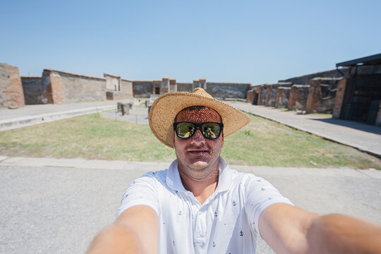 Man tourist in hat and sunglasses making selfie at Pompeii ancient city, Italy.