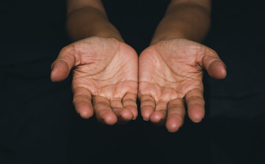 Woman with open hands praying for God's blessing in black background