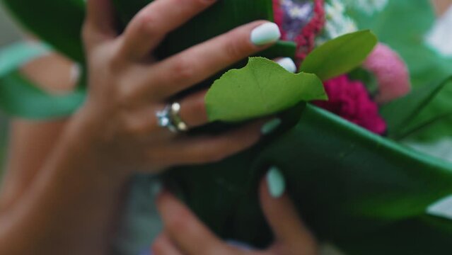 Unrecognizable Turkish bride in sleeveless wedding dress holding her bridal bouquet with both hands, showing her new wedding ring and beautiful nails. High quality 4k footage