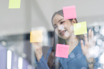 Business female employee with many conflicting priorities arranging sticky notes commenting and...