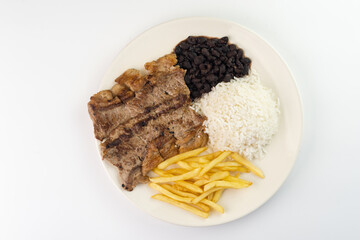 Delicious executive dish of beef steak, rice, beans, french fries and green salad with lettuce, tomato and onion accompanied by farofa and vinaigrette. Typical Brazilian food. Selective focus