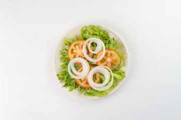 Fresh salad with lettuce, tomato and onion on white background. Top view. Typical Brazilian food. Selective focus