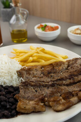 Delicious executive dish of beef steak, rice, beans, french fries and green salad with lettuce, tomato and onion accompanied by farofa and vinaigrette. Typical Brazilian food. Selective focus