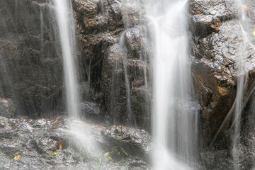 A cascading waterfall cascades against a black rock slab background.