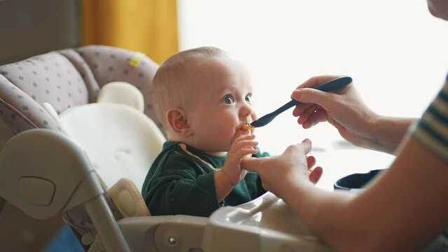 baby newborn eats. happy family dream weaning concept. dirty mess baby boy eating vegetables. baby son eats on a feeding chair dirty face. naughty dirty babe indulges while feeding indoors