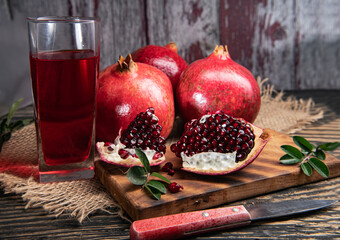 pomegranate fruit with leaves and pieces of pomegranate on a wooden board, dark vintage background...
