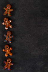 Gingerbread man. Christmas cookies covered with chocolate and colored icing sugar. Dark gray background. Top view. Copy space