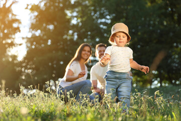 Fototapeta premium Happy cute baby daughter near her parents playing in park