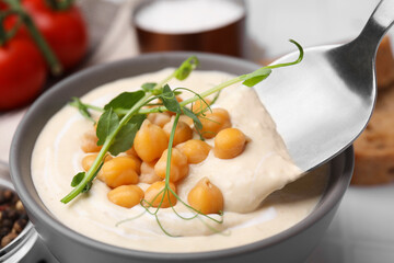 Eating tasty chickpea soup on table, closeup