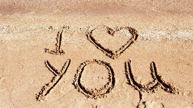 Inscription I love you on sand. Shooting on the beach.