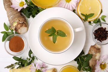Flat lay composition with cup of delicious tea, honey and ginger on white wooden table