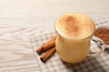 Delicious eggnog with cinnamon on wooden table, closeup. Space for text