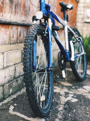 Mountain blue bike stands near the wall of the old house