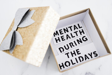 mental health during the holidays text inside of festive Christmas gift box decoration, managing overwhelm and expectations during the holiday season