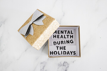 mental health during the holidays text inside of festive Christmas gift box decoration, managing overwhelm and expectations during the holiday season