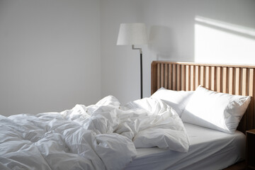 Sunlight falls on an empty room with untidy bedding